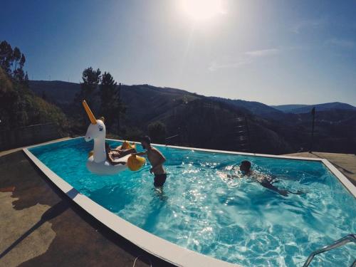 twee mensen in een zwembad met speelgoed in het water bij Mountainhome Casa Cancelinha in Soito