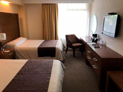 a hotel room with two beds and a television at Hotel Las Trojes in Aguascalientes