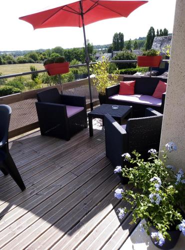 a deck with chairs and tables and an umbrella at gite odeau in Sargé-sur-Braye