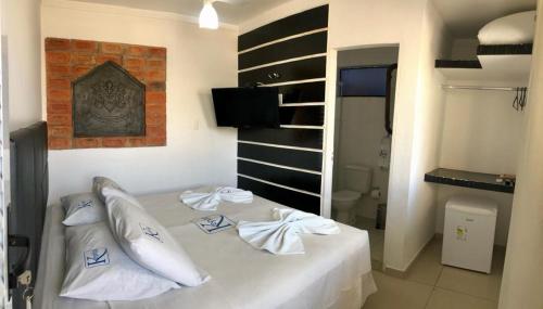 1 dormitorio con 1 cama con sábanas y almohadas blancas en Pousada Kepha, en Guarujá