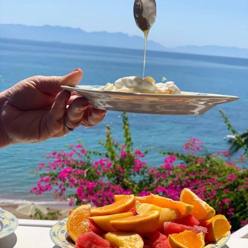 a person holding a plate of fruit with a spoon at Ilaira Apartments in Khránoi
