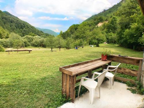 a wooden table with two chairs and a field at Kamp Vrbnica in Pluzine