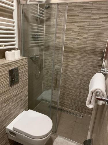 a bathroom with a toilet and a glass shower at Enter Rooms in Zagreb