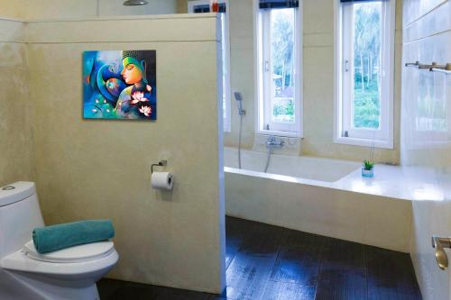 a bathroom with a toilet and a bath tub and a painting at Palm View Villa in Lamai