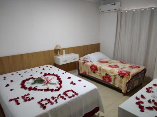 Habitación de hotel con 2 camas con flores rojas. en ALUGUEL POR TEMPORADA JCL 2, en Gramado