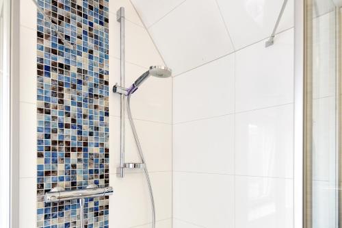 y baño con ducha de azulejos azules. en Solskin, en Tönning
