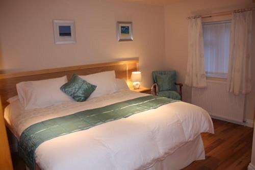 a bedroom with a large white bed and a chair at The Anvil Lodge in Shifnal