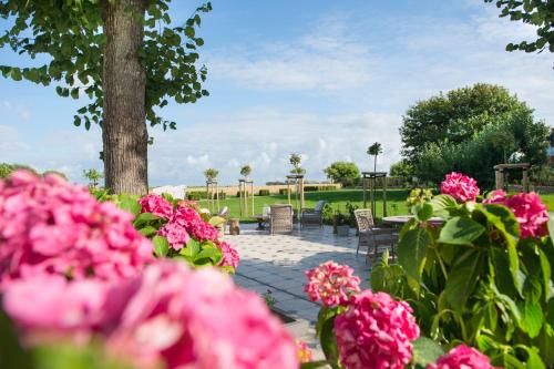 a garden with pink flowers and tables and chairs at Hotel Hof Galerie in Morsum