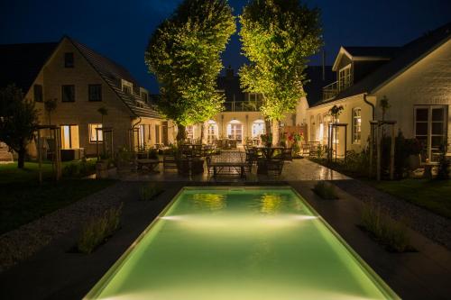 a swimming pool in the yard of a house at night at Hotel Hof Galerie in Morsum