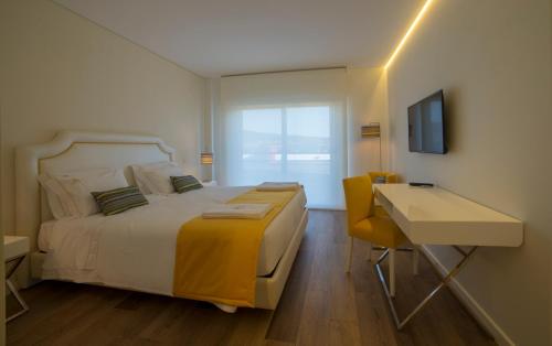 a bedroom with a bed and a desk and a television at Terrace Serra Hotel in Covilhã