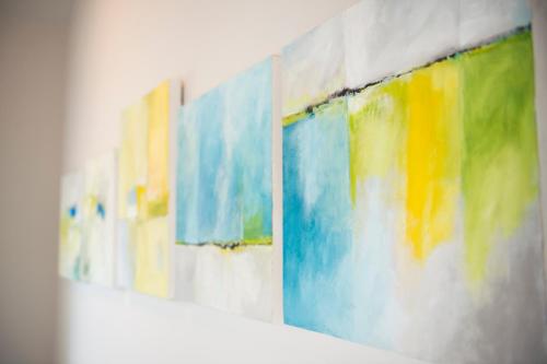 a row of colorful paintings hanging on a wall at Hotel Hof Galerie in Morsum
