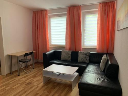 a living room with a black leather couch and orange curtains at Pension an der Zeche in Essen