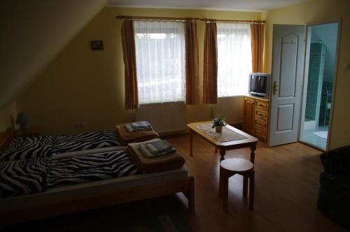 um quarto com uma cama com estampa de zebra e uma mesa em Hóvirág Panzió em Porva