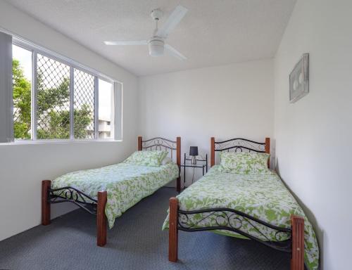 two beds in a room with two windows at Edmund Shores U5 58 Edmund Street in Caloundra