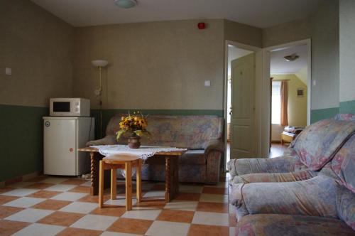 uma sala de estar com um sofá, uma mesa e um frigorífico em Hóvirág Panzió em Porva