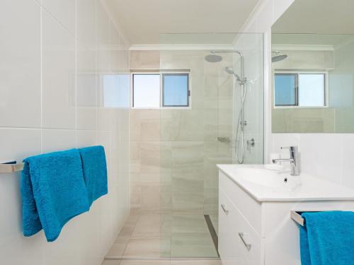 een witte badkamer met een douche en een wastafel bij Explorer Cove Unit 6 31 Kennedy Pde in Caloundra