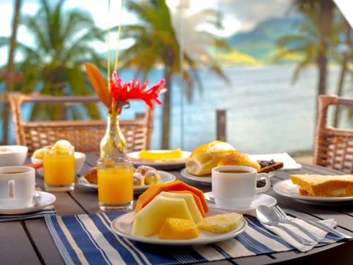 a table topped with plates of food and orange juice at Hotel Mercedes in Ilhabela
