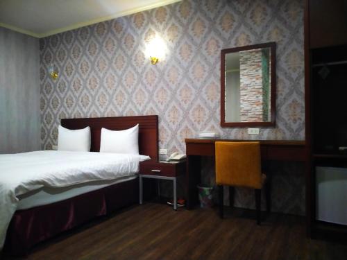 Schlafzimmer mit einem Bett, einem Schreibtisch und einem Spiegel in der Unterkunft 欣悅商務旅店 in Toufen