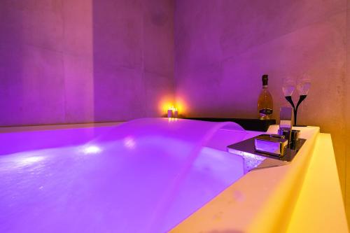 Habitación púrpura con bañera y botella de vino en Al Castello Luxury B&B, en Reggio Calabria