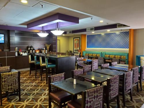 a restaurant with tables and chairs and a bar at La Quinta by Wyndham Memphis Airport Graceland in Memphis