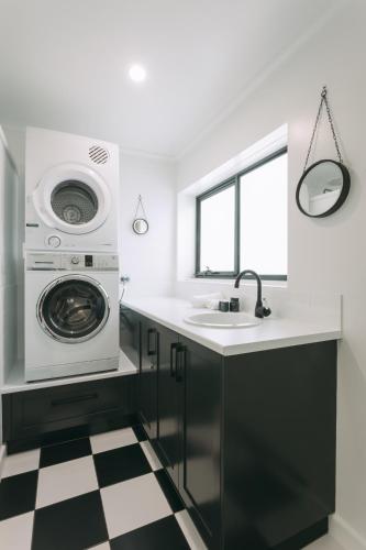 a kitchen with a washing machine and a sink at Deco Beach Luxury Apartments in Port Lincoln