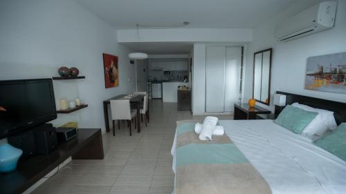 a bedroom with a bed and a tv and a kitchen at Sea Point By D&G in Carilo