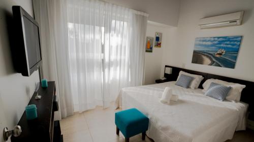 a bedroom with a white bed and a blue stool at Sea Point By D&G in Carilo