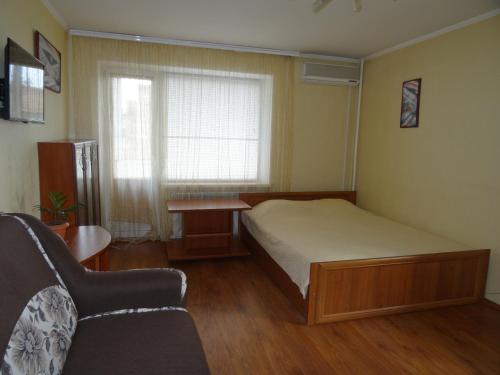 a bedroom with a bed and a couch and a window at Apart Gagarina in Kropyvnytskyi