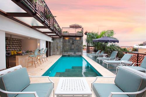 uma piscina com cadeiras e um bar num pátio em Hotel Capellán de Getsemaní em Cartagena das Índias