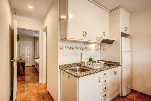 a kitchen with white cabinets and a sink at Granada I Apartments in Patalavaca