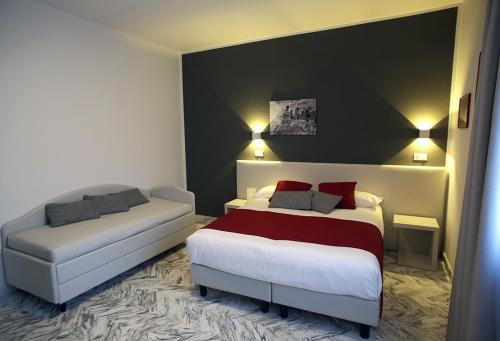 una camera d'albergo con due letti e un divano di Mikeme a Carrara