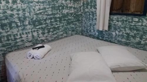 a room with two beds with a towel and a black belt at A Casinha Pequenina in Monte Verde