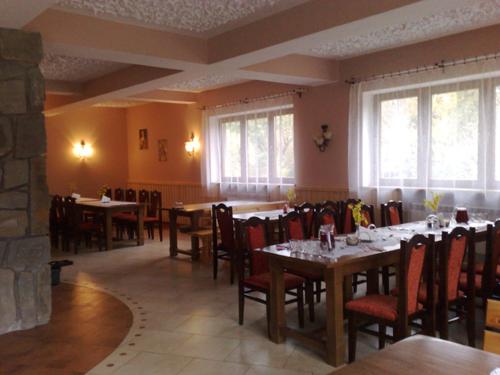 a dining room with tables and chairs and windows at Dom Wypoczynkowy Podhalanka in Białka Tatrzańska