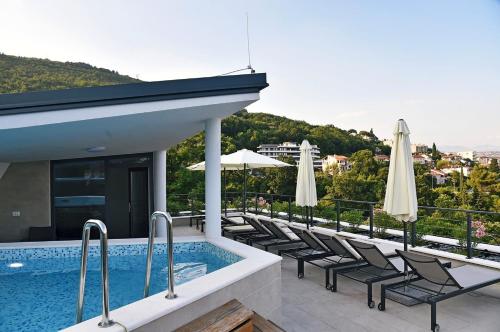 a swimming pool with chairs and umbrellas on a building at Apartments in Villa Ziza, rooftop swimming pool in Opatija