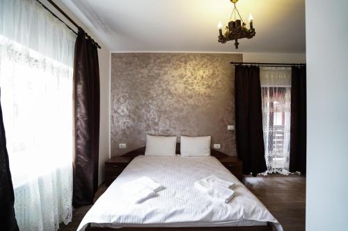 a bedroom with a bed with white sheets and a chandelier at Pensiunea Trei Lalele in Moisei