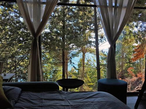 a bedroom with a bed and a large window with trees at La Quinta Glamping - Lago de Tota in Cuítiva