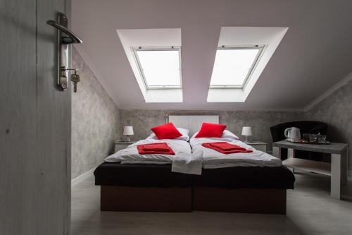 a bedroom with a bed with two red pillows at Penzion Bardejov in Bardejov