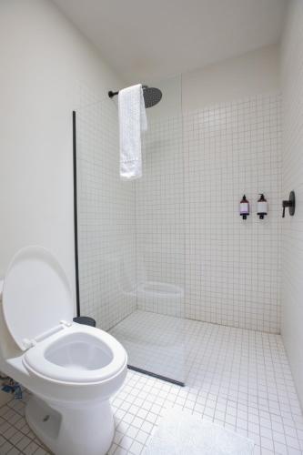 a white bathroom with a toilet and a shower at Casa Ixaya by Barrio México in Guadalajara