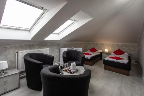 a attic room with two beds and chairs and skylights at Penzion Bardejov in Bardejov