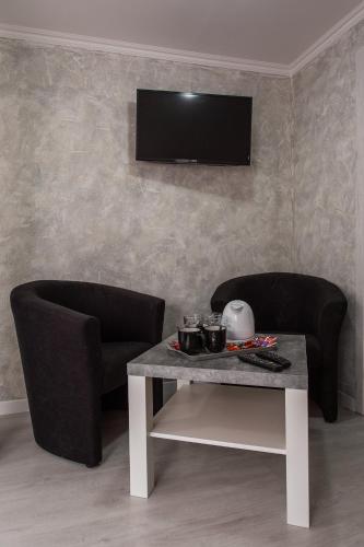a living room with two chairs and a table and a television at Penzion Bardejov in Bardejov