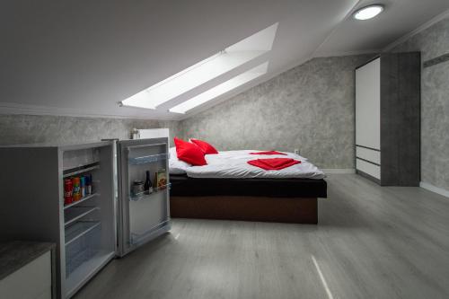 a bedroom with a bed with red pillows and a refrigerator at Penzion Bardejov in Bardejov