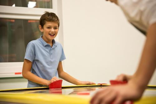 a young boy standing at a ping pong table at Hotel Lesana in Vysoké Tatry