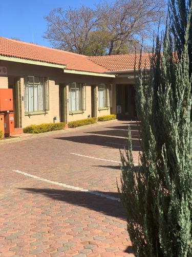 a building with a red roof and a brick driveway at Polokwane Lodge in Polokwane