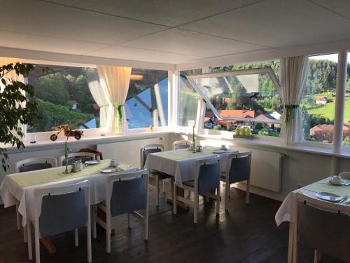 a restaurant with white tables and chairs and windows at Hotel-Berggasthof Schwarzwaldperle in Sasbachwalden