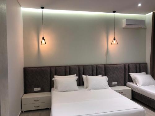 薩蘭達的住宿－Hotel LIDI，一间卧室配有两张带白色枕头和灯光的床。