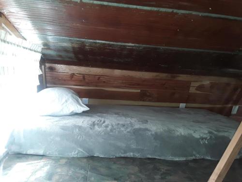 a bed in a room with a wooden wall at Amish made cedar cabin with a loft on a buffalo farm close to the Buffalo River in Marshall