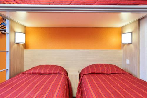 a bedroom with two beds and orange walls at Premiere Classe Montreuil in Montreuil