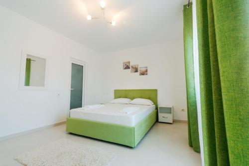 a white bedroom with a bed and a green curtain at Casa Erty in Eforie Nord