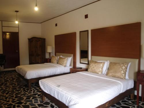 a hotel room with two beds with white sheets at Hotel Vitorina Cholula in Cholula