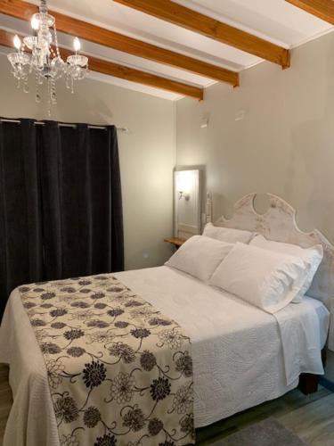 a bedroom with a white bed and a chandelier at Hostel Chaman in Osorno